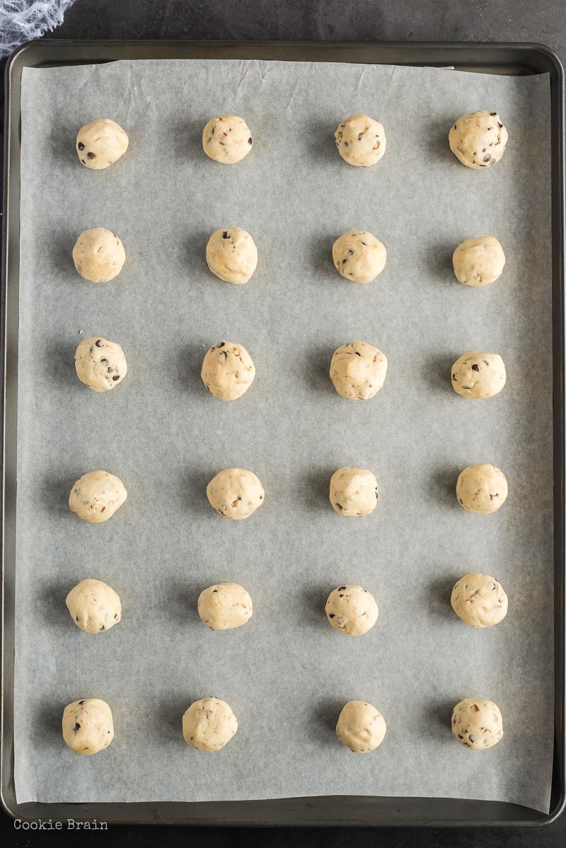 cookie dough balls lined up on baking sheet