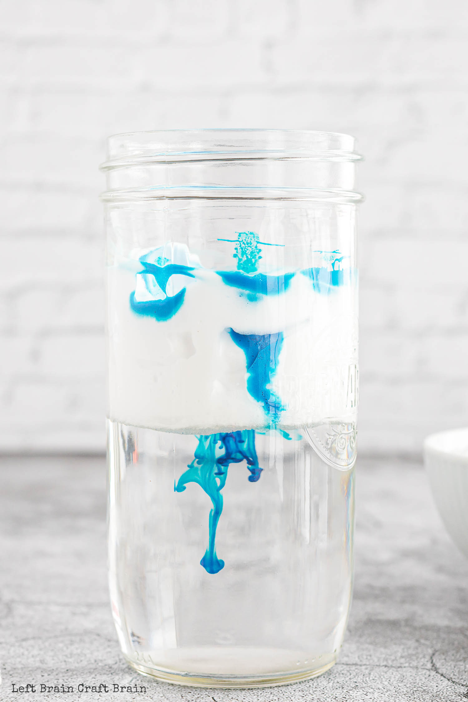 shaving cream and water in a jar with blue food coloring falling through it