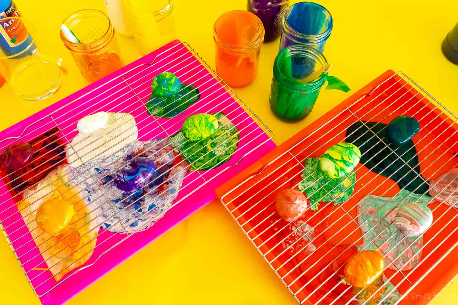 pour painted garden rocks on wire rocks on trays with jars of paint