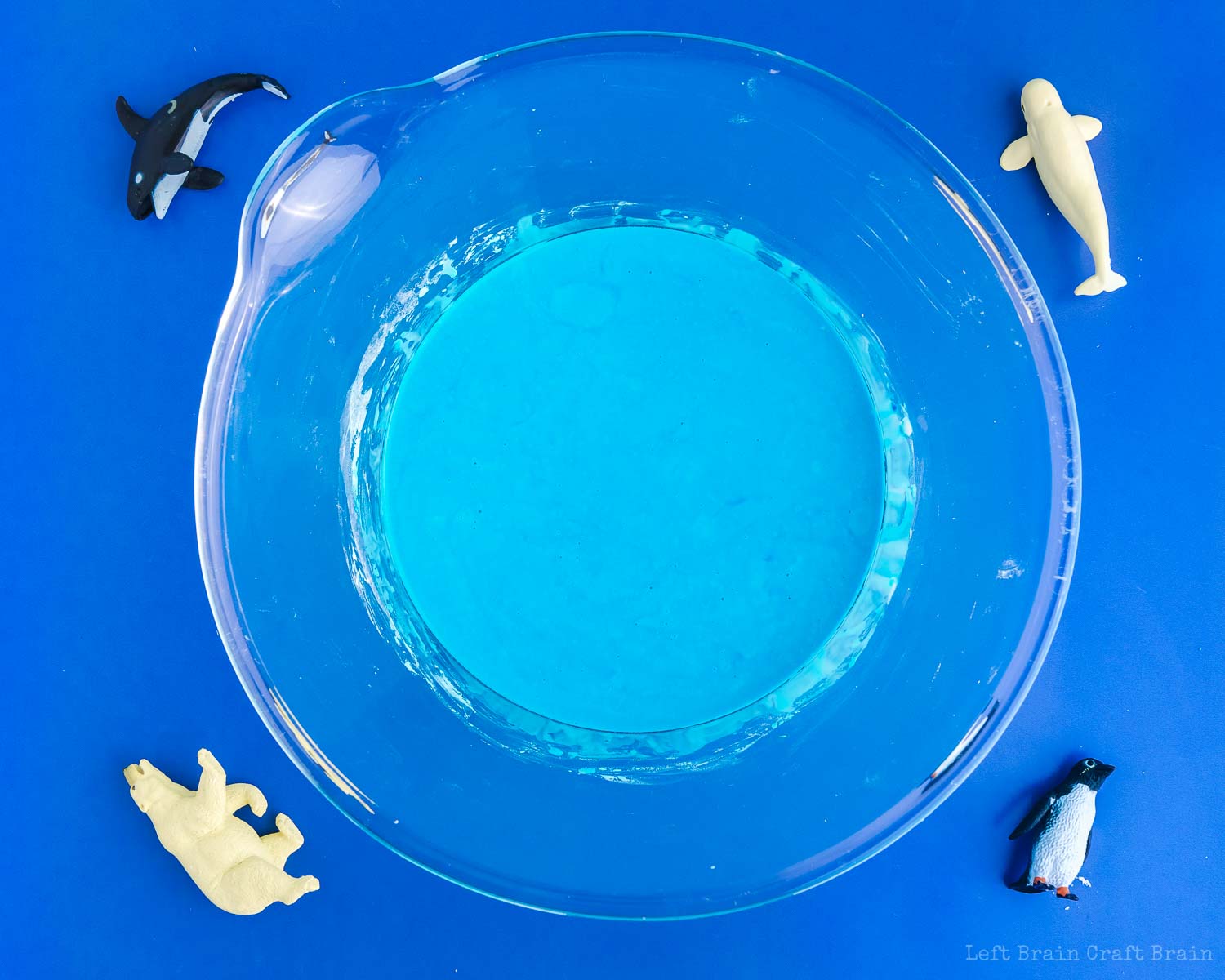 blue oobleck in glass bowl with plastic polar animal toys whale orca polar bear penguin